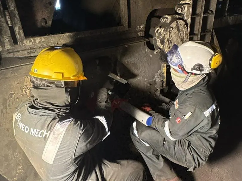 Two technicians installing a belt cleaner at the head chute