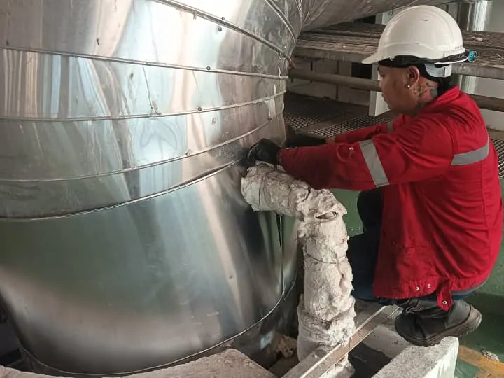 Technician wrapping insulation around a pipe bend